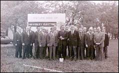 A group of people standing in front of a sign

Description automatically generated with medium confidence