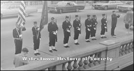 A group of men in uniform standing on a sidewalk

Description automatically generated