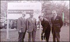 A group of men standing in front of a sign

Description automatically generated with medium confidence