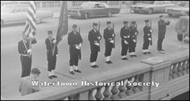 A group of men in uniform standing on a sidewalk

Description automatically generated